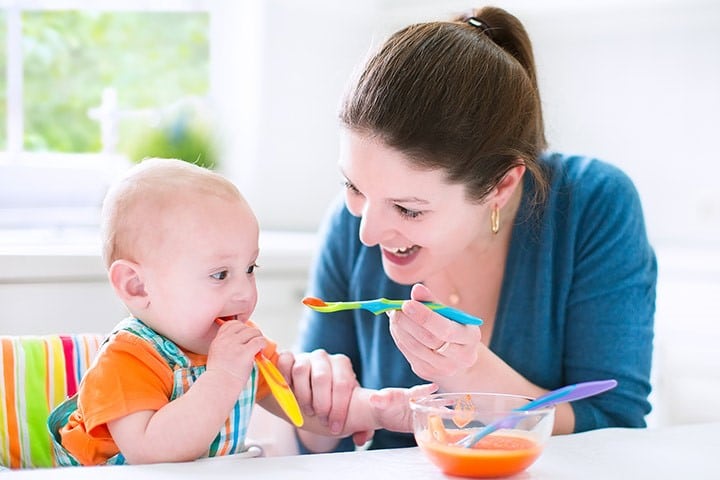 Young attractive mother feeding her cute baby son