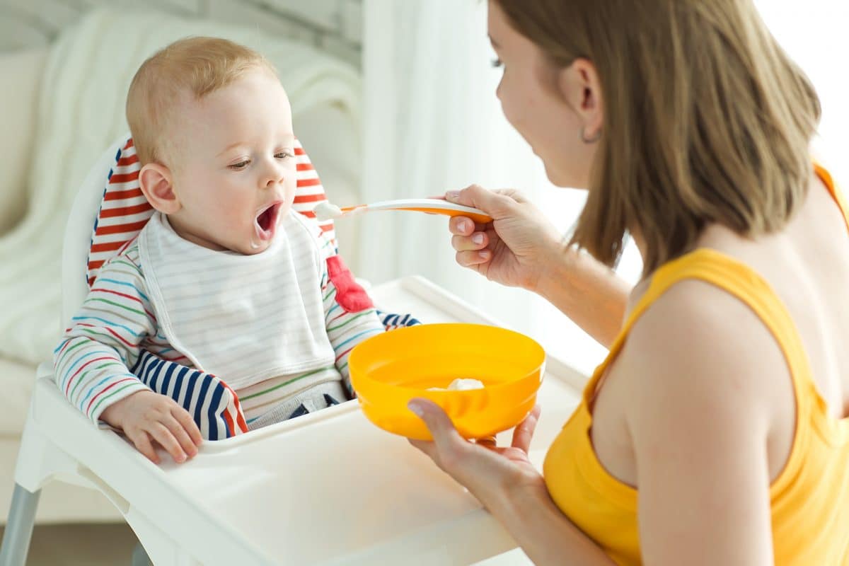 Mother feeding child in a high chair