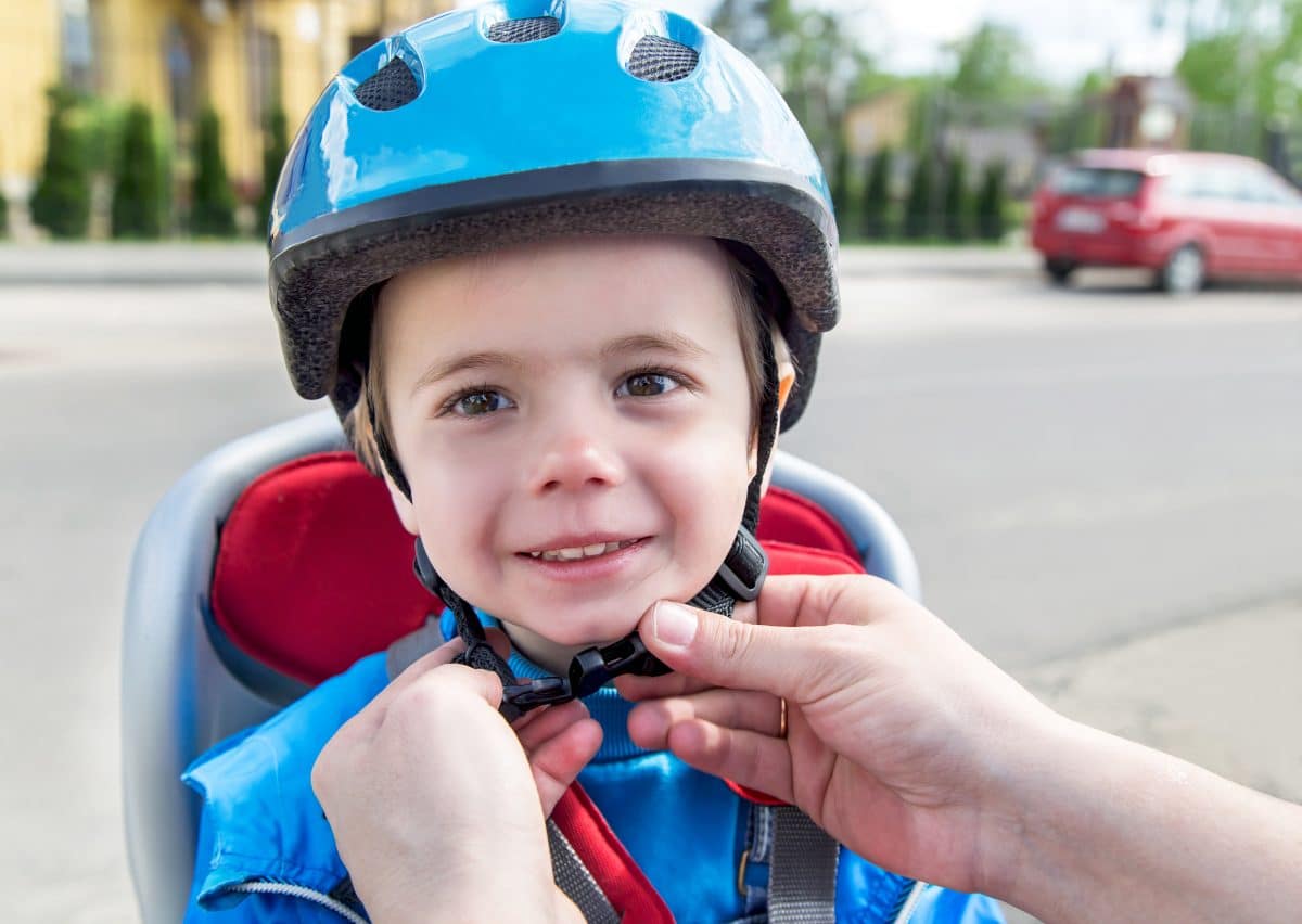 Parent putting bike helmet on toddler