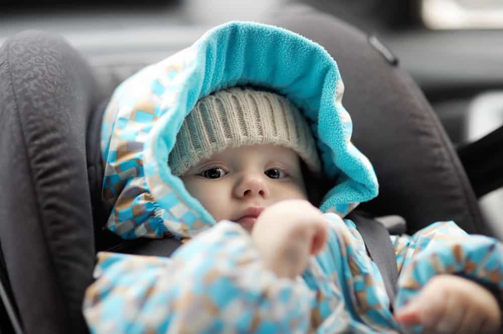 Baby in a car seat covered in clothes