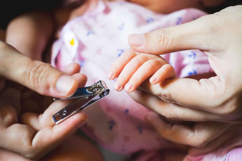 Close up of parent cutting infant’s fingernails