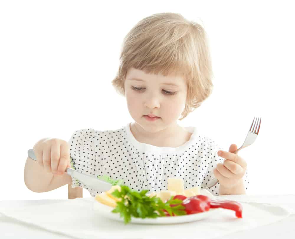 Toddler using a white plate and white placemat to eat a meal