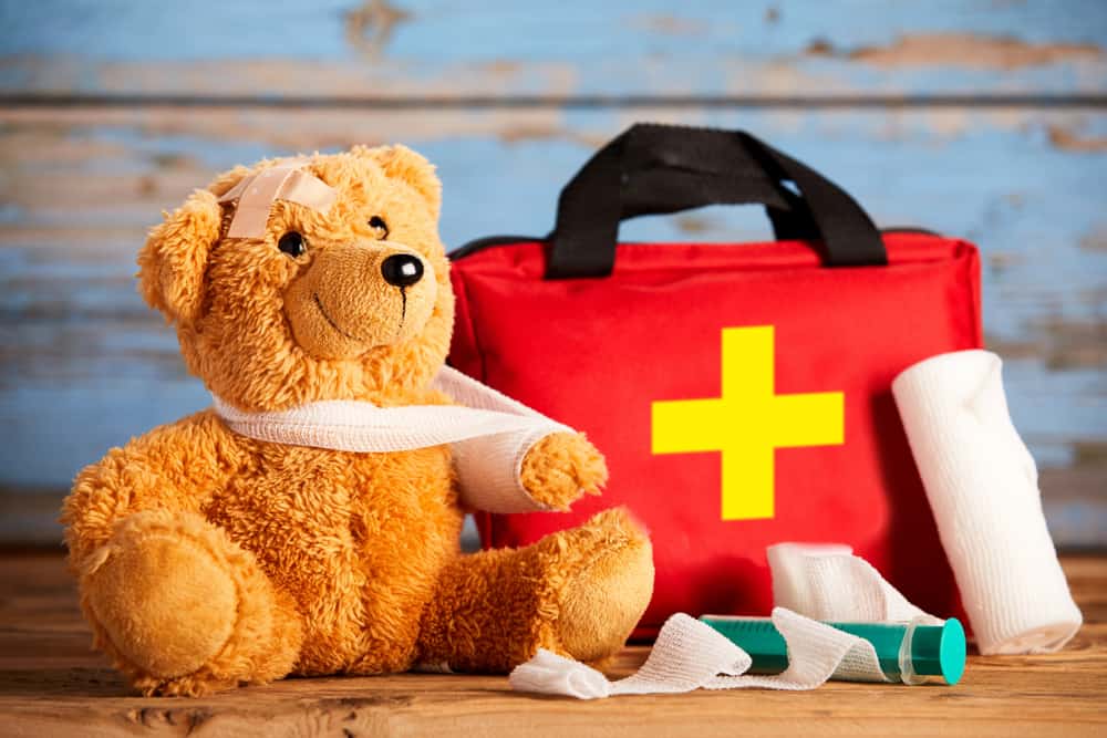 a teddy bear with a bandage and first aid kit
