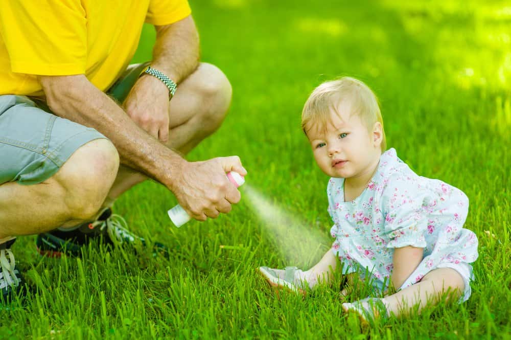 baby being sprayed with insect repellant