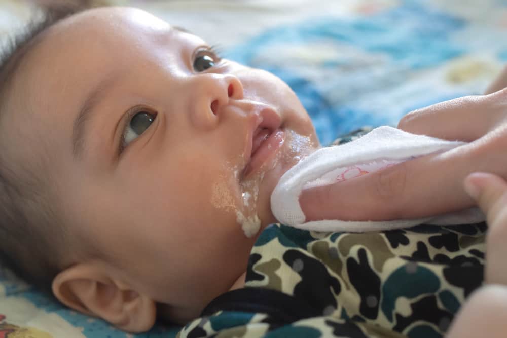 baby spitting up face being wiped