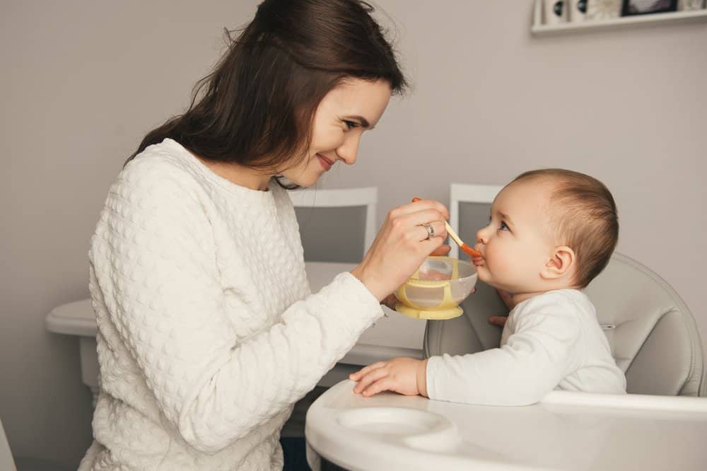 Mother in white sweater feeding her child