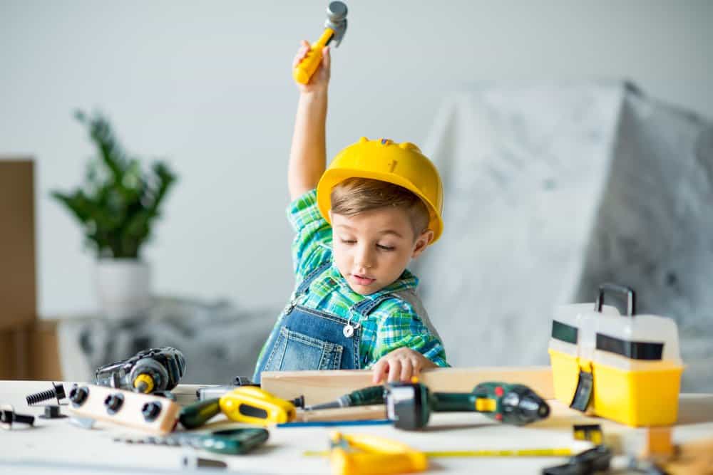 little boy wearing a hard hat plays with tools