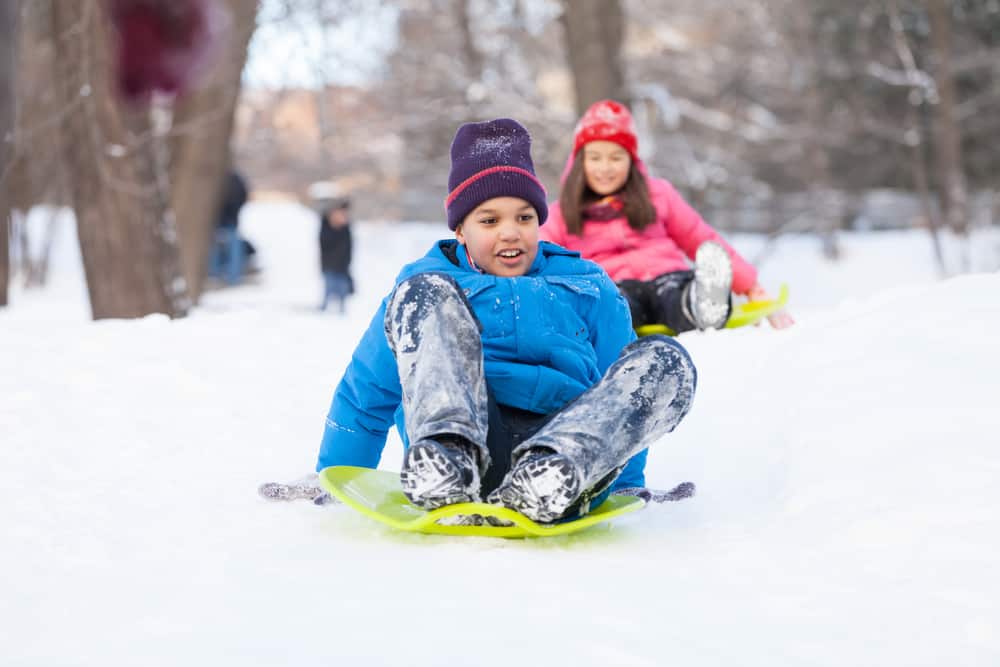 boy and girl on sleds in the park