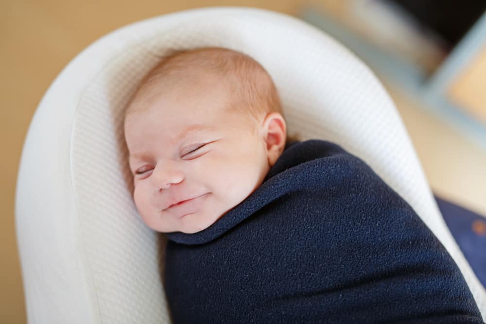baby smiling in a swaddle