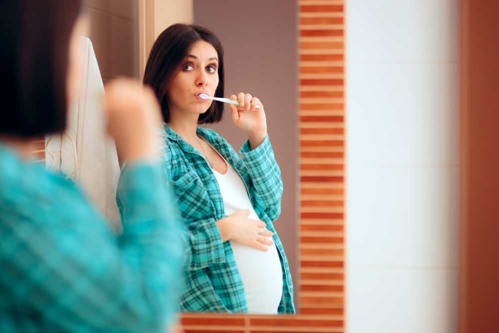 pregnant woman brushing her teeth