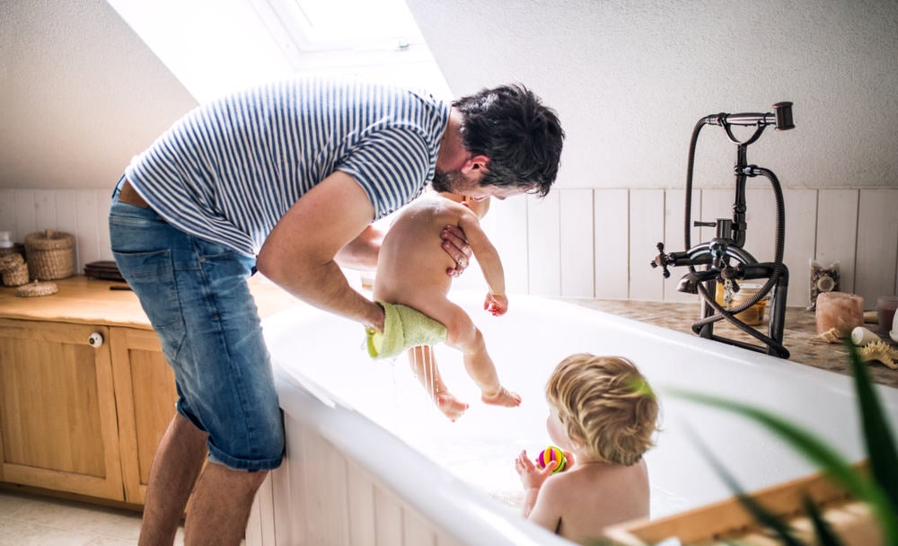 dad washing two babies in the tub