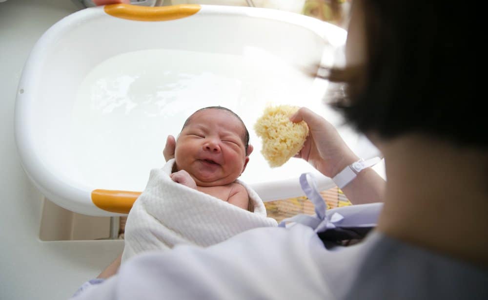 Mother washes newborn with sponge