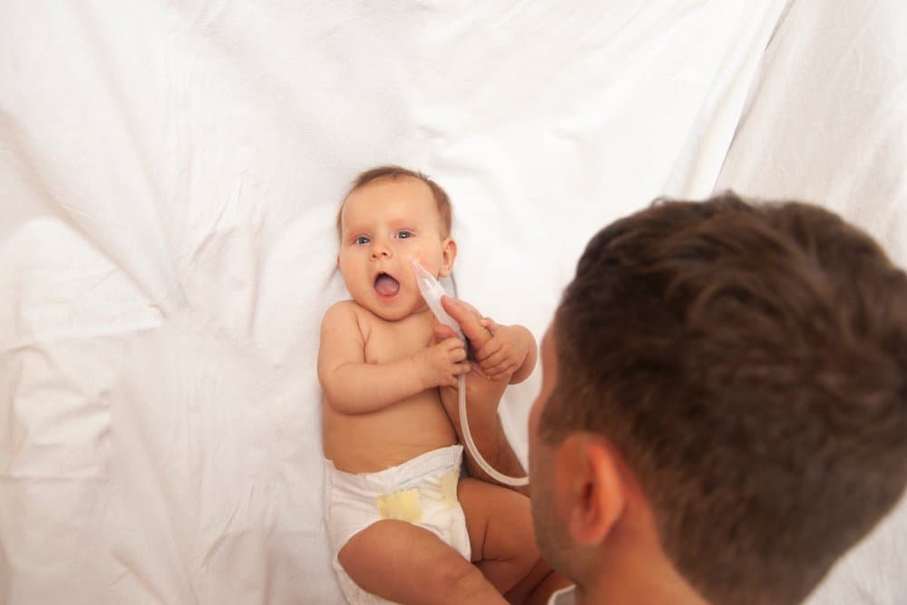 Father using nasal aspirator on baby