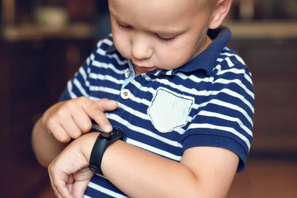 child checks fitness tracker watch