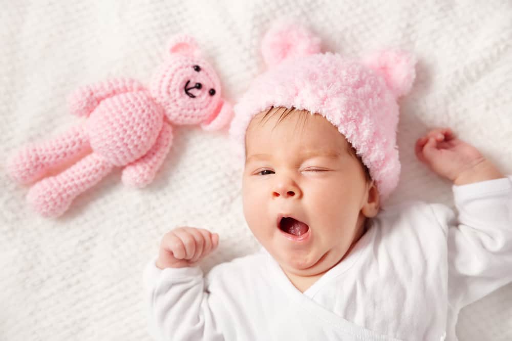 a baby yawning in her crib