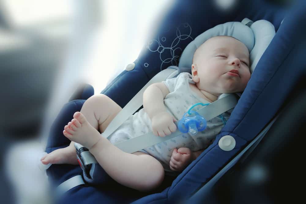 a baby in a car seat asleep in the car