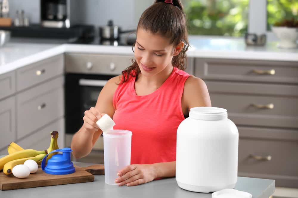 a woman preparing a protein shake in her kitchen