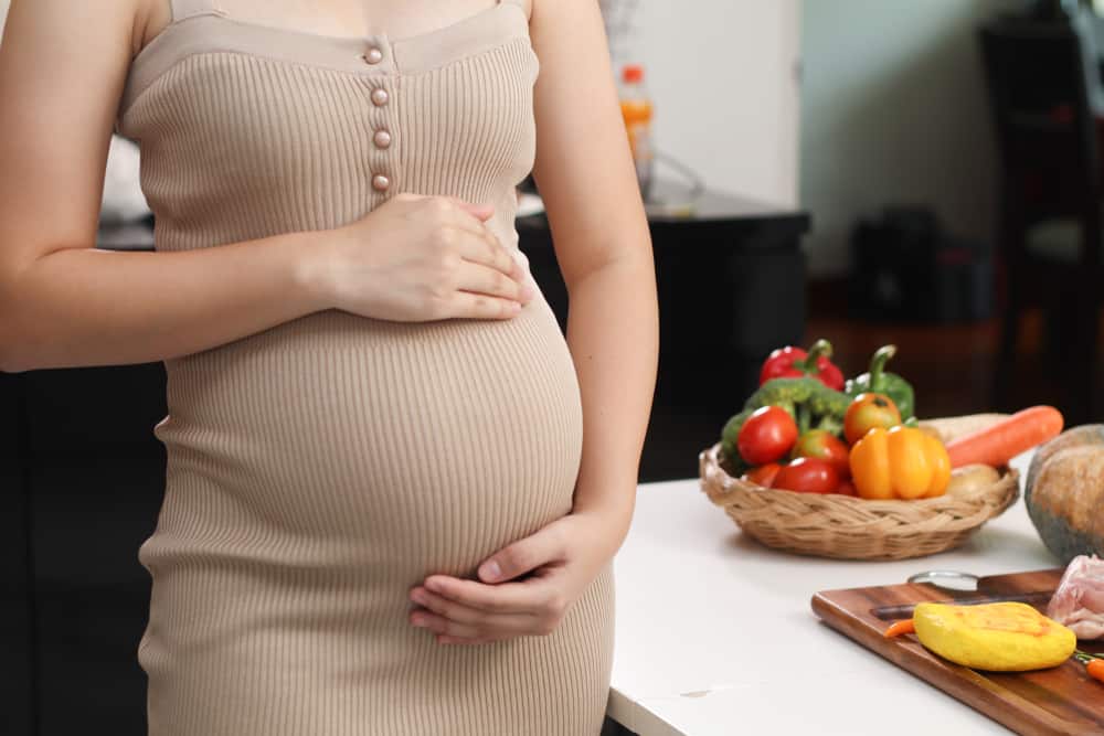 a pregnant woman with a lot of healthy foods behind her