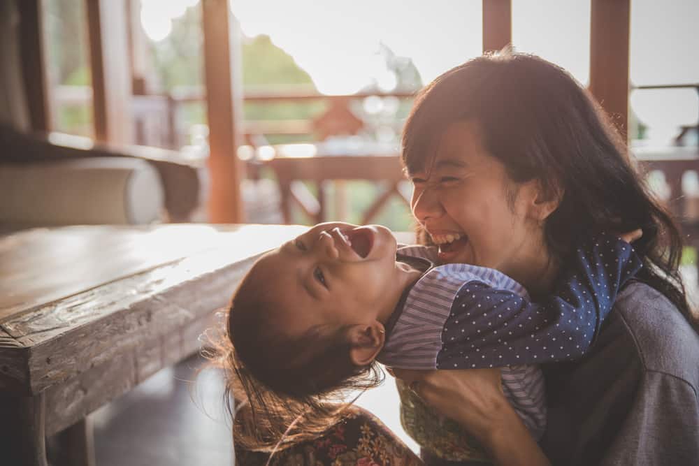 laughing mother holding happy toddler outside