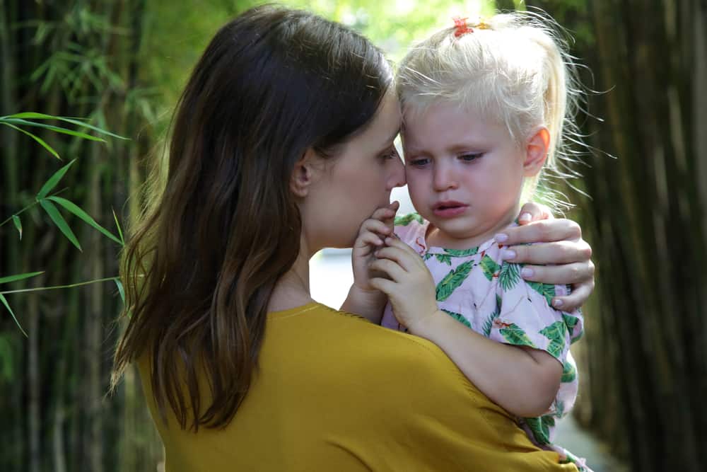 mother holding and soothing crying girl toddler