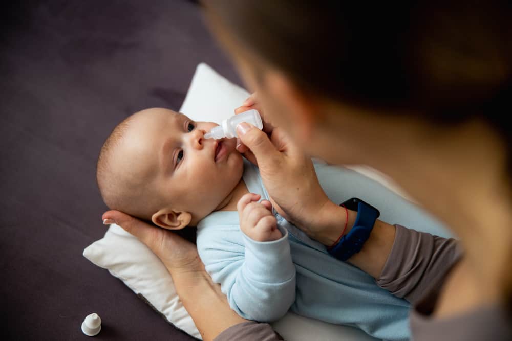 a woman gives her baby some nasal drops