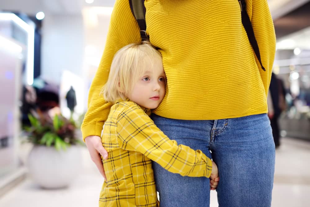 child hugging onto their parent’s leg