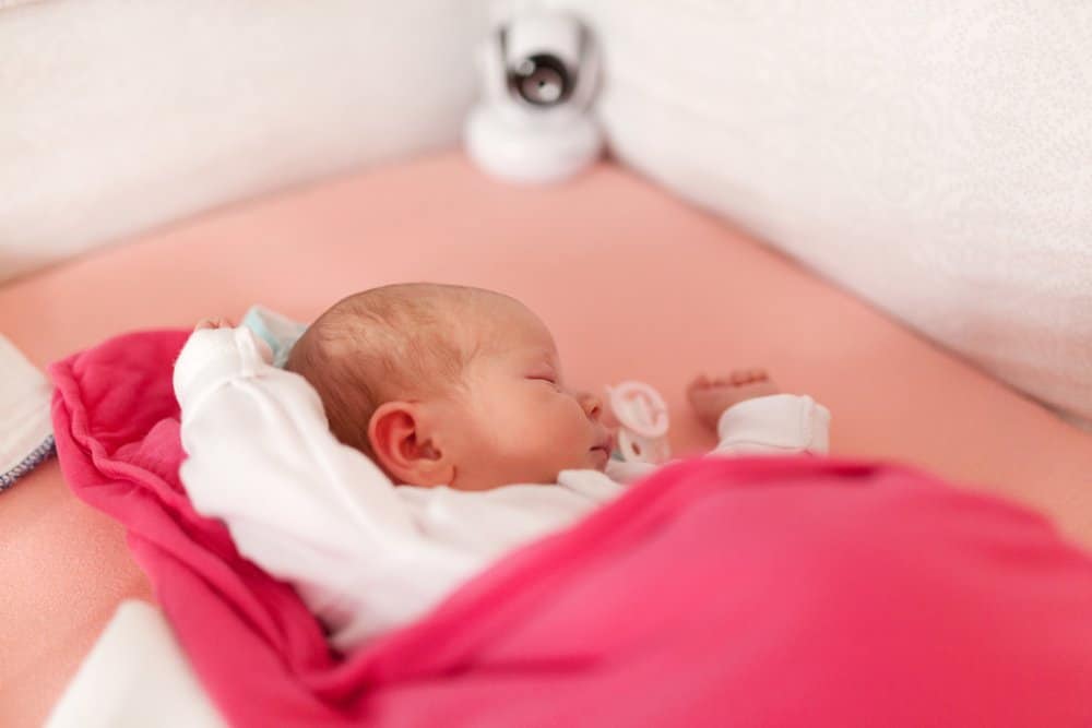 baby sleeping next to baby monitor