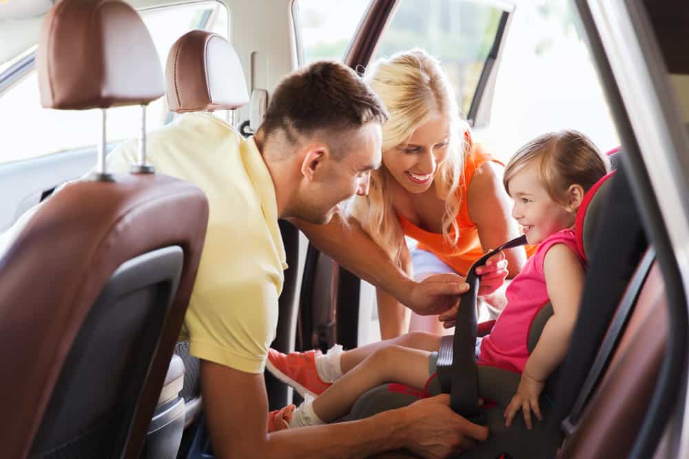 family putting child in car seat