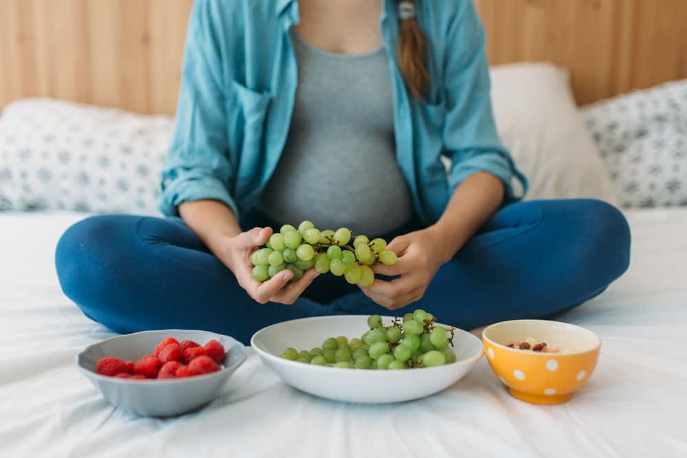 pregnant woman holding grapes