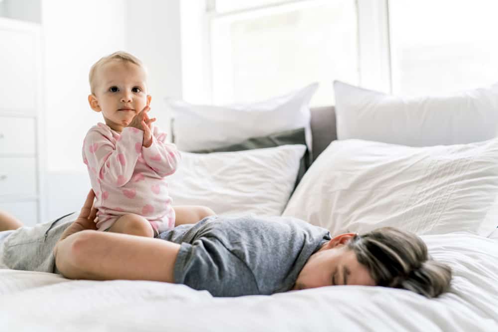 tired father on bed with small baby